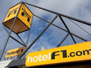 A yellow sign with the text "hotelF1.com" and a logo indicating a hotel. - hotelF1 Avignon Centre Courtine Gare TGV (Avignon)