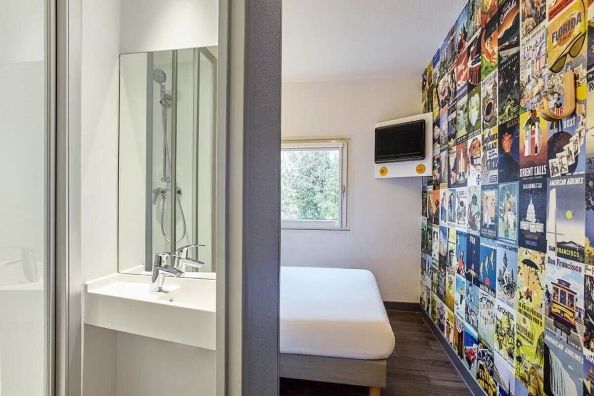 A bathroom with a shower, a sink, and a bench. A wall-mounted TV is visible.