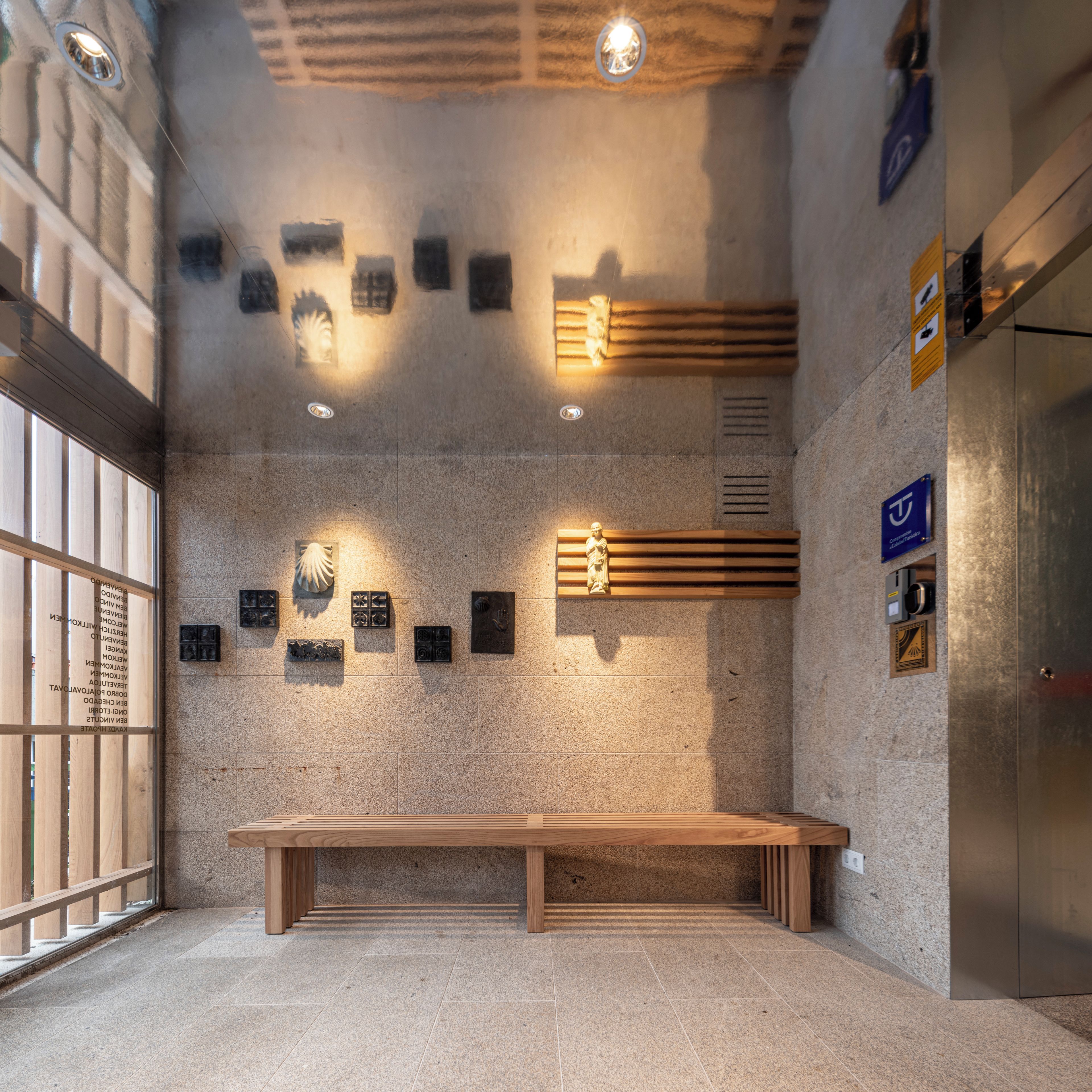 A modern interior with a wooden bench, stone walls, and various plaques.