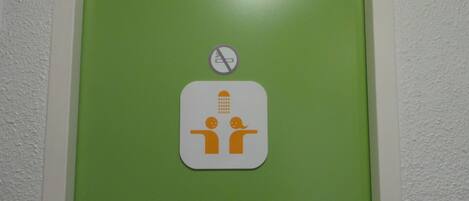 Señal de baño con símbolo de prohibido fumar e icono de ducha.