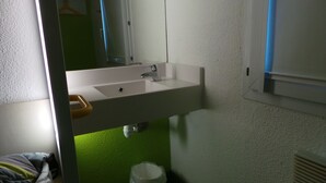 Ein Badezimmer mit einem weißen Waschbecken, grünem Boden und einem Spiegel darüber.