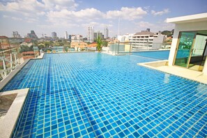 A rooftop infinity pool with a city view, surrounded by glass railings and a modern building structure.