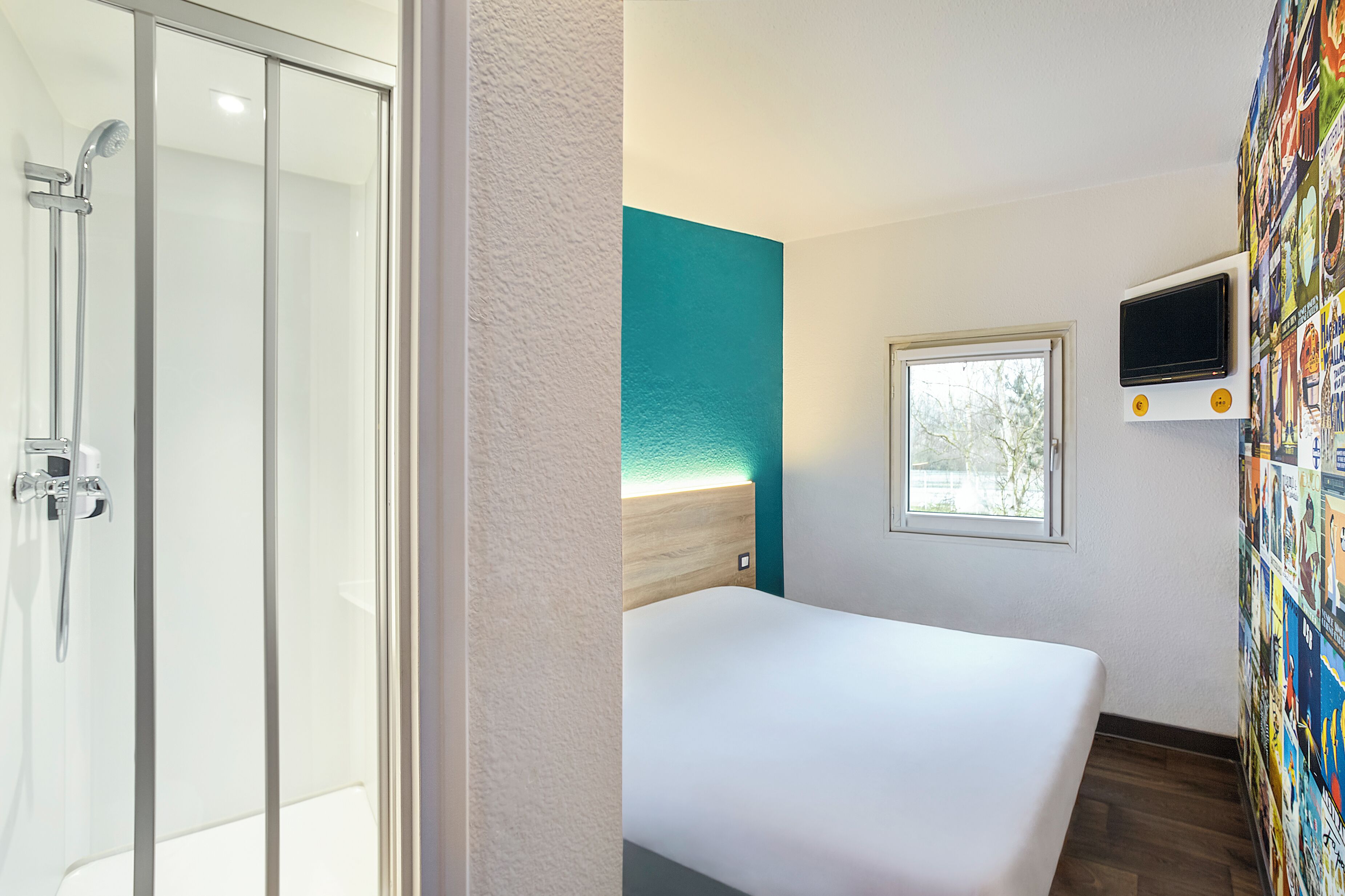 A hotel room with a shower, a bed, a TV, and a window.