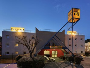 Um hotel com uma placa visível, uma escadaria e um estacionamento.