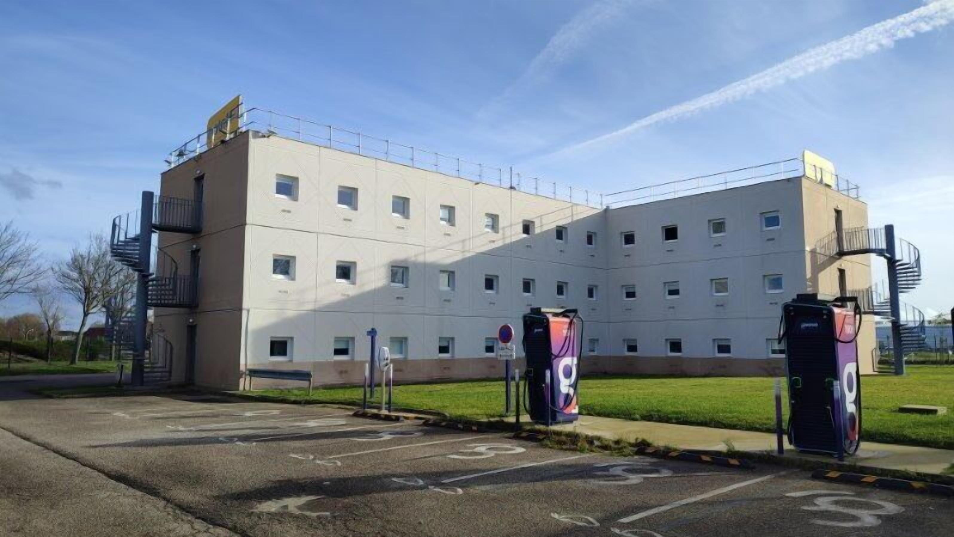 A multi-story building with a parking lot in front.