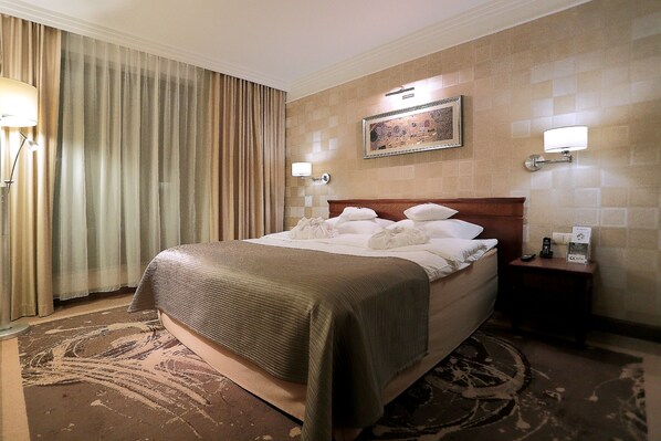 A hotel room with a large bed, a nightstand, a lamp, and a painting on the wall. - Hotel Esperanto (Bialystok)
