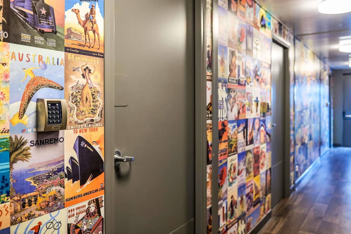 A hallway with travel posters on the walls and a door with a keypad lock.