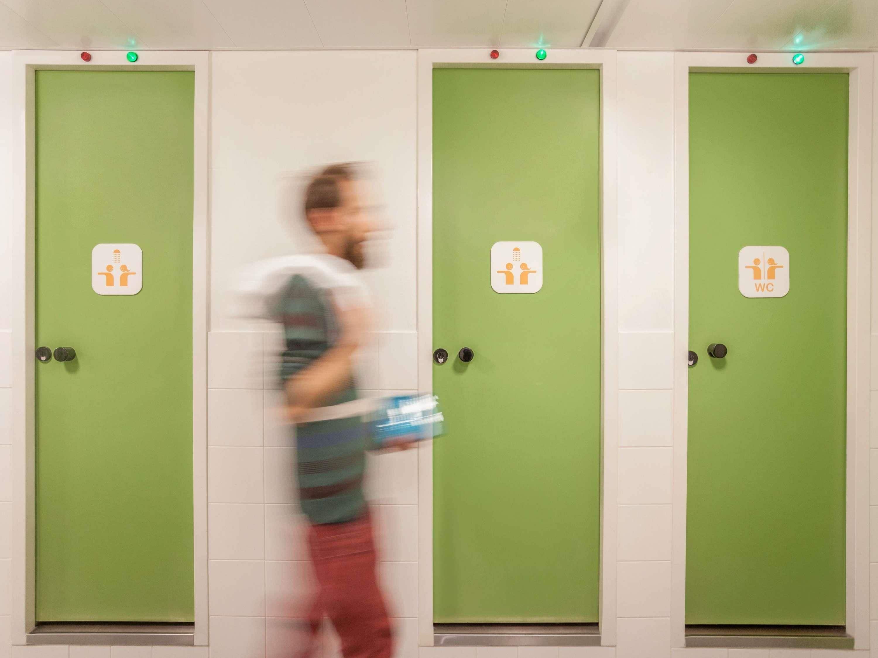 Een rij groene deuren met een pictogram voor toilet, wat openbare toiletten aangeeft.