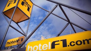 Un letrero amarillo con el texto 'hotelF1.com' y un logotipo que muestra la letra 'F' y el número '1'.