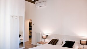 A bedroom with a bed, bedside lamps, a mirror, and a radiator. - Giuturna Boutique Hotel (Rome)