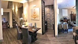 A hotel lobby with a staircase, dining area, and a seating area with a view of the city. - Giuturna Boutique Hotel (Rome)
