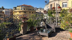 A rooftop terrace with potted plants, a glass table, and outdoor furniture. - Giuturna Boutique Hotel (Rome)