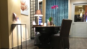 A modern interior with a piano, a glass table with a candle, and a blue curtain in the background. - Giuturna Boutique Hotel (Rome)