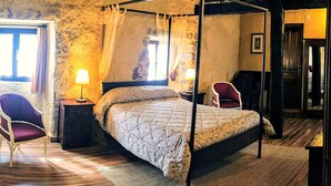 A four-poster bed in a rustic room with stone walls and wooden beams. - Posada Torre-Palacio de los Alvarado (Merindad de Montija)