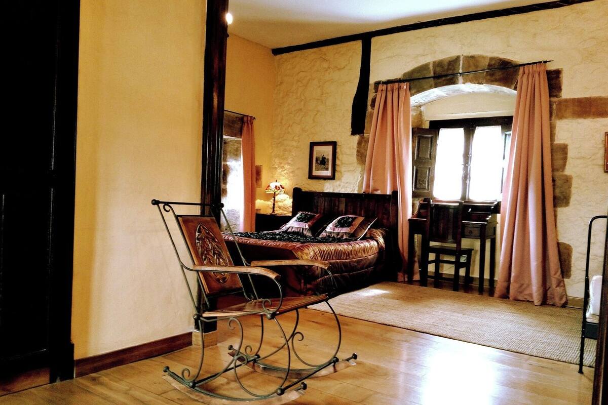 A cozy room with a rocking chair, a bed with a headboard, and a desk with a chair.