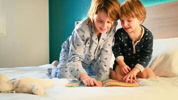Dos personas leyendo un libro en una cama con un osito de peluche.