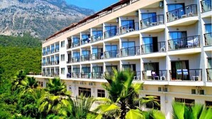 A multi-story hotel with balconies, set against a mountainous backdrop. - Magic Sun Hotel (Kemer)