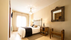A bedroom with a bed, bedside table, mirror, and a bench.