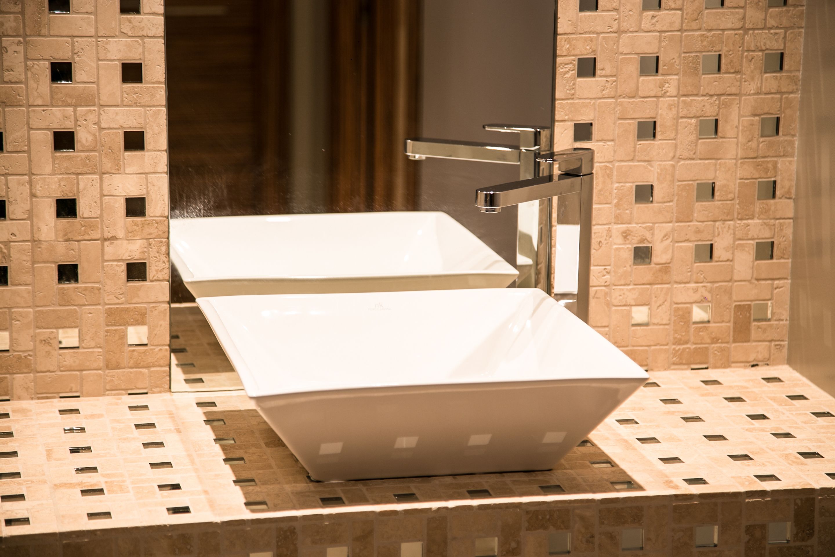 Un baño moderno con un lavamanos rectangular y una pared espejada.