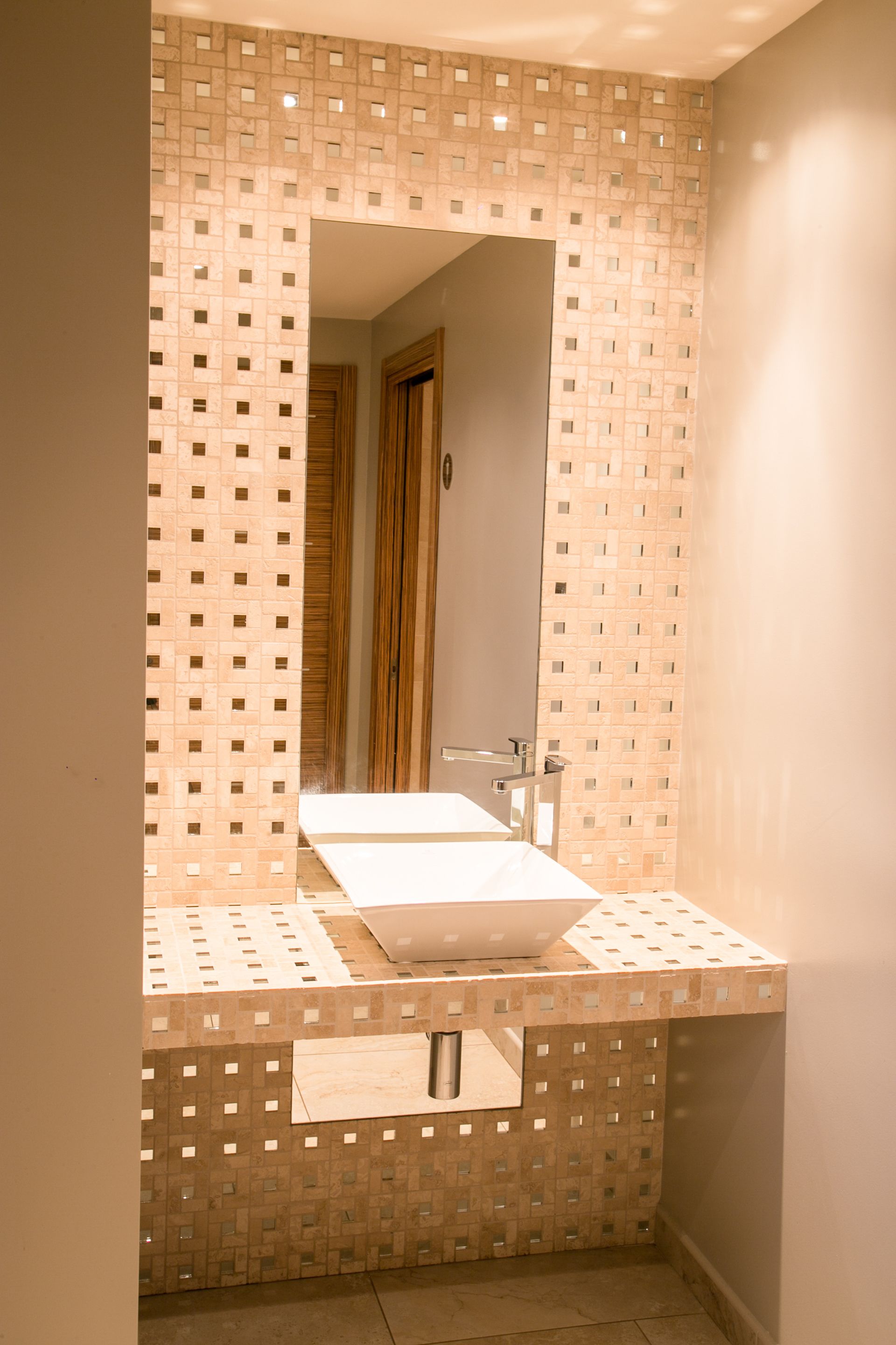 Un baño con pared de azulejos, lavabo y espejo.