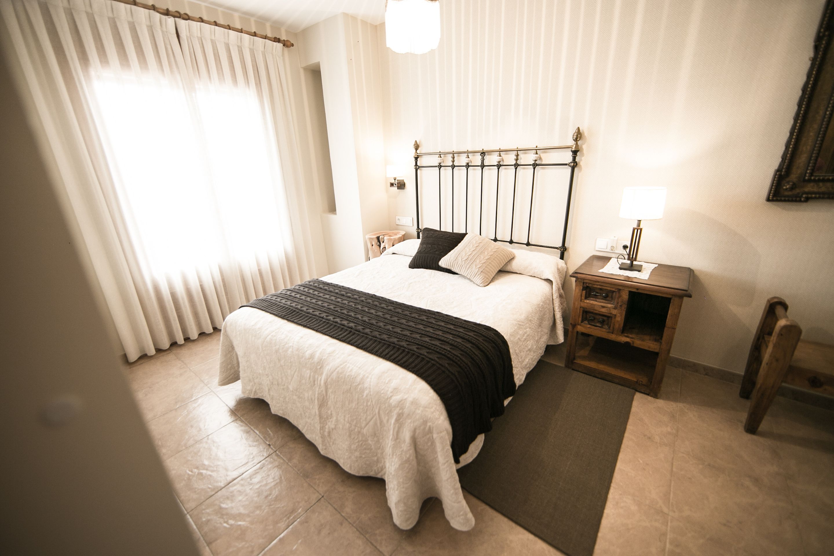 Un dormitorio ordenado con cama, mesitas de noche y mesilla.