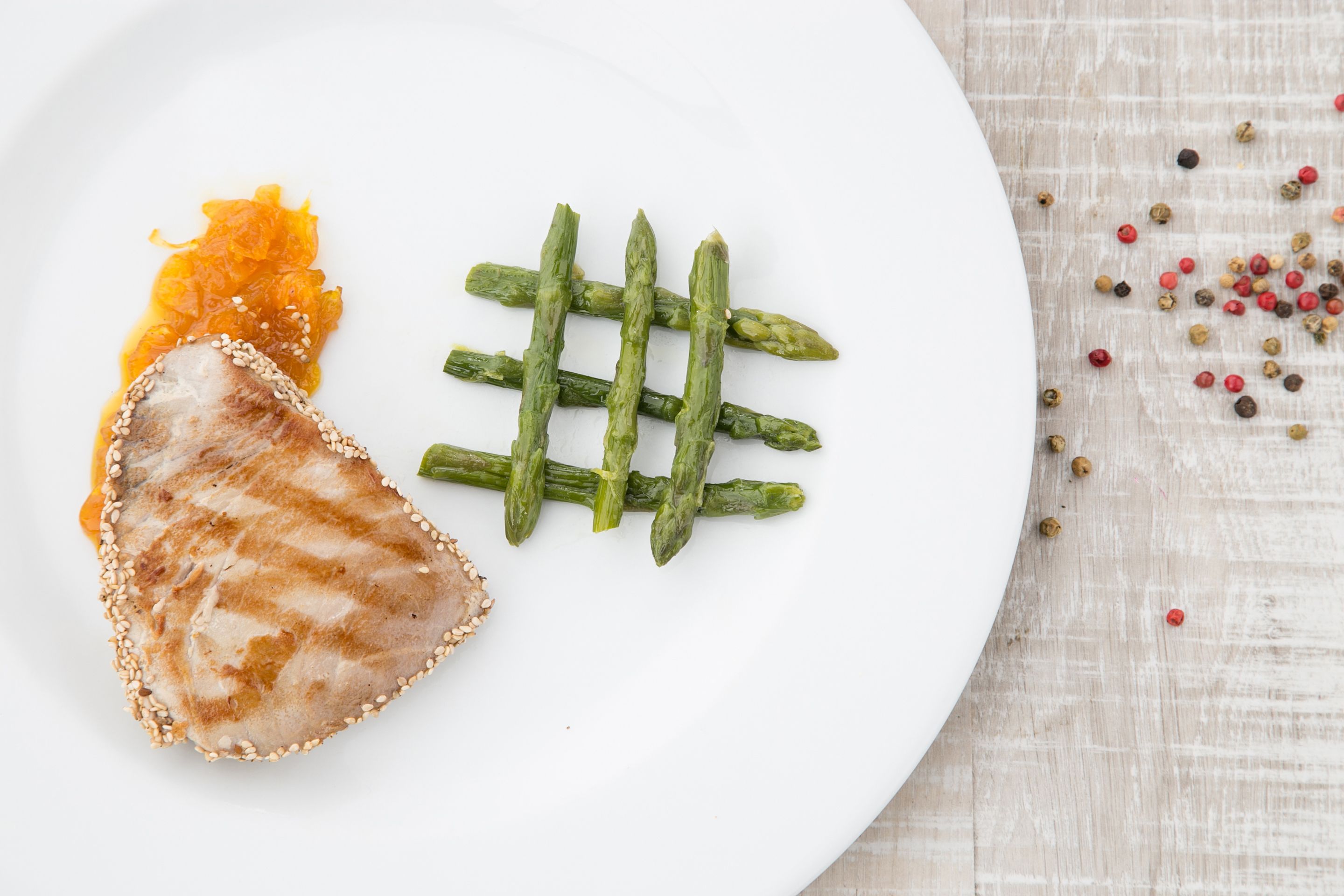 A white plate with grilled meat, asparagus, and a small amount of sauce.