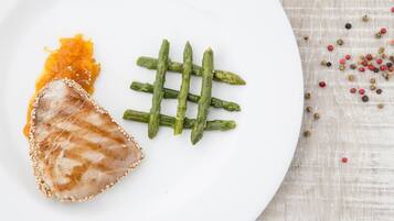 A white plate with grilled meat, asparagus, and a small amount of sauce.