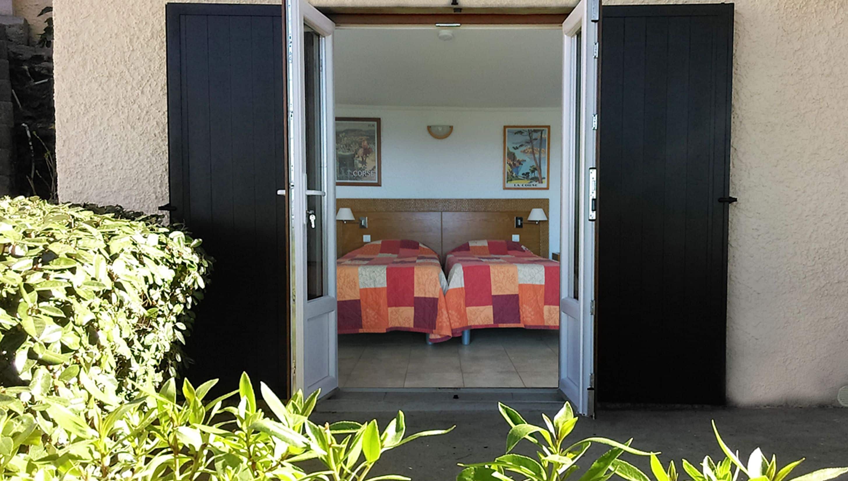 A hotel room with two beds, a wooden headboard, and a small window.