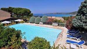 A pool with lounge chairs, surrounded by greenery and overlooking a coastal view. - Domaine Saint Pierre (Cargese)