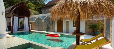 Una piscina al aire libre, sombrillas, sillones reclinables de piscina