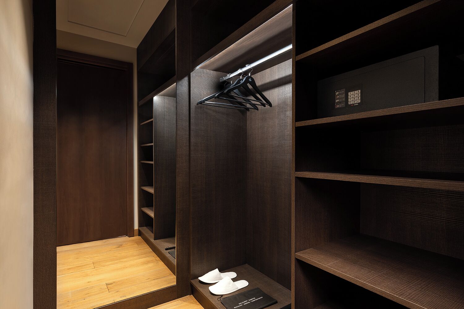 A walk-in closet with wooden shelves and a shoe rack.