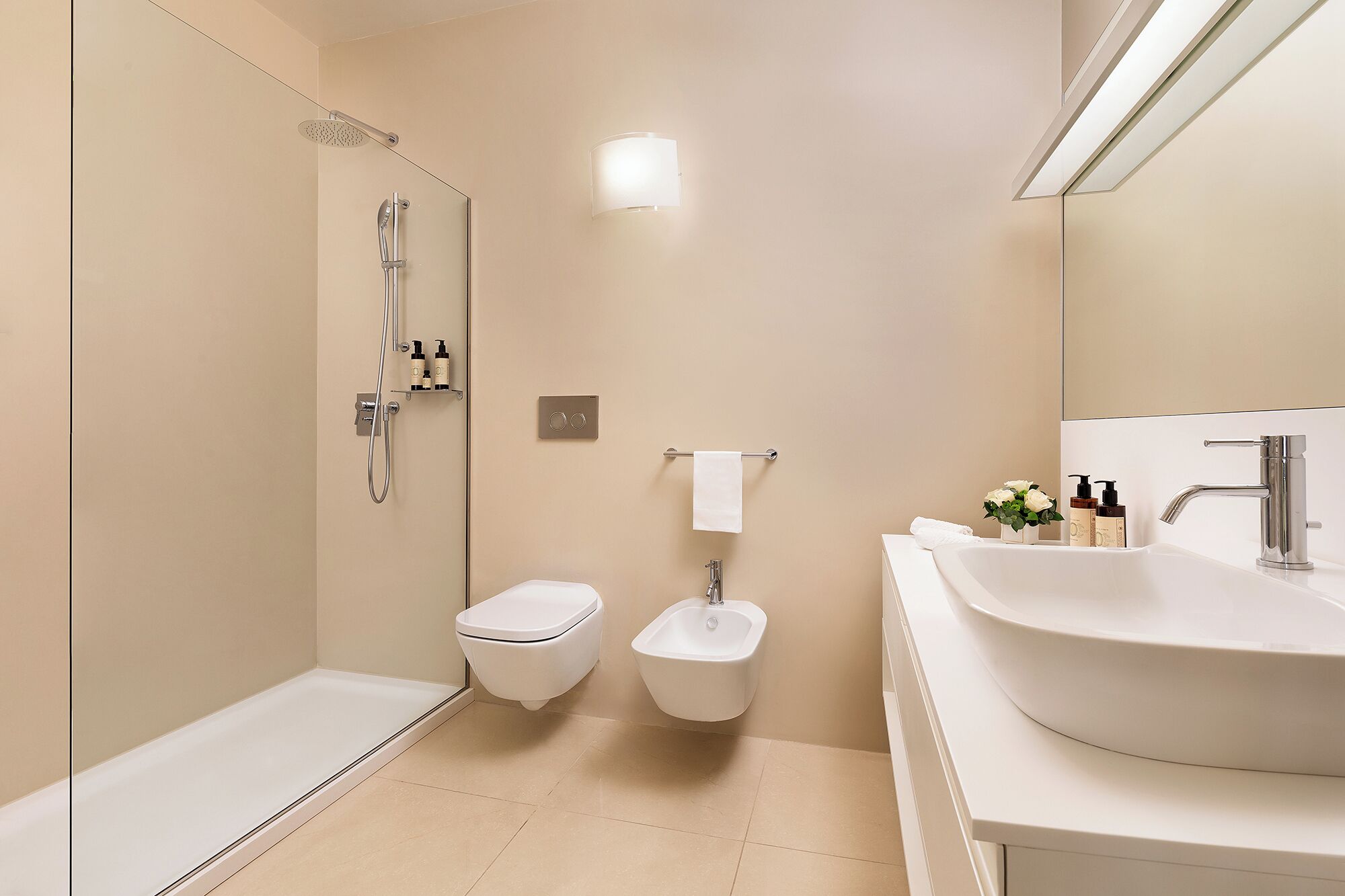 Un baño moderno con ducha, inodoro, bidé y un lavamanos amplio.