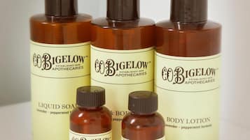 Fire flasker Bigelow hudplejeprodukter, herunder flydende sæbe, shampoo og bodylotion, står arrangeret på en hylde.