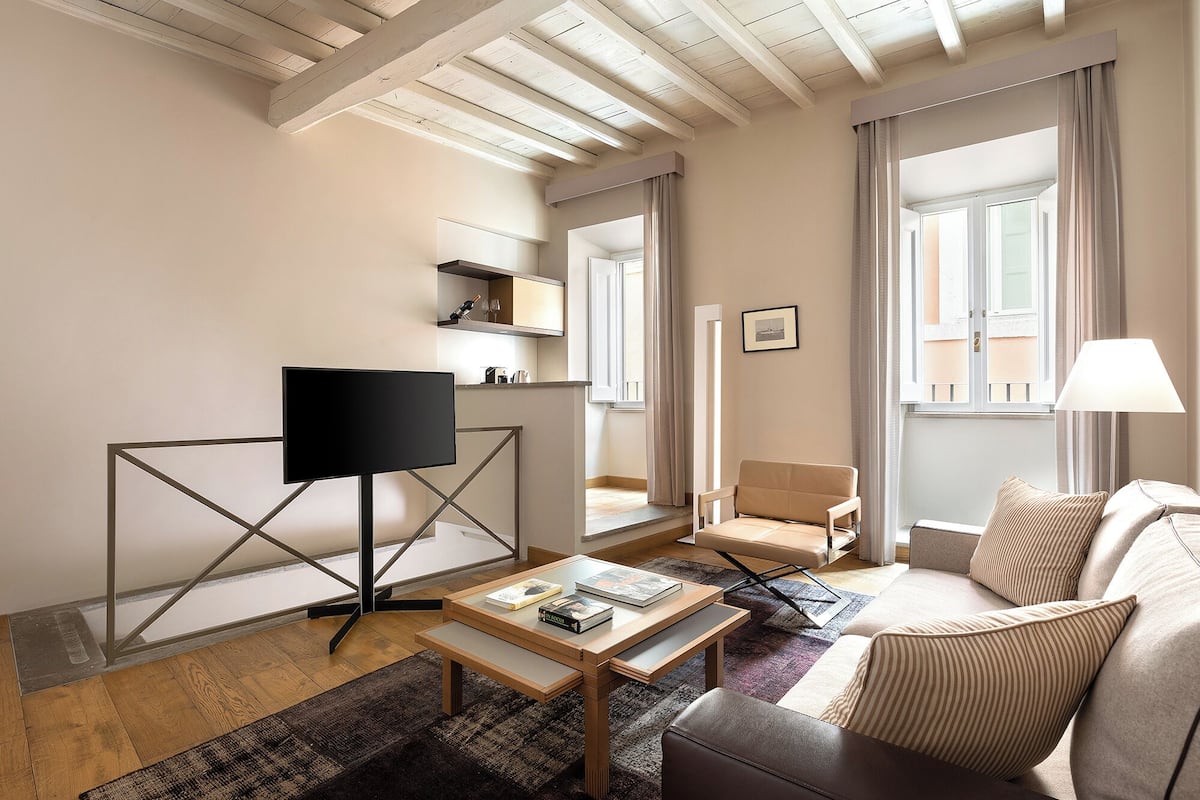 A modern living room with a flat-screen TV, a sofa, a coffee table, and a chair.