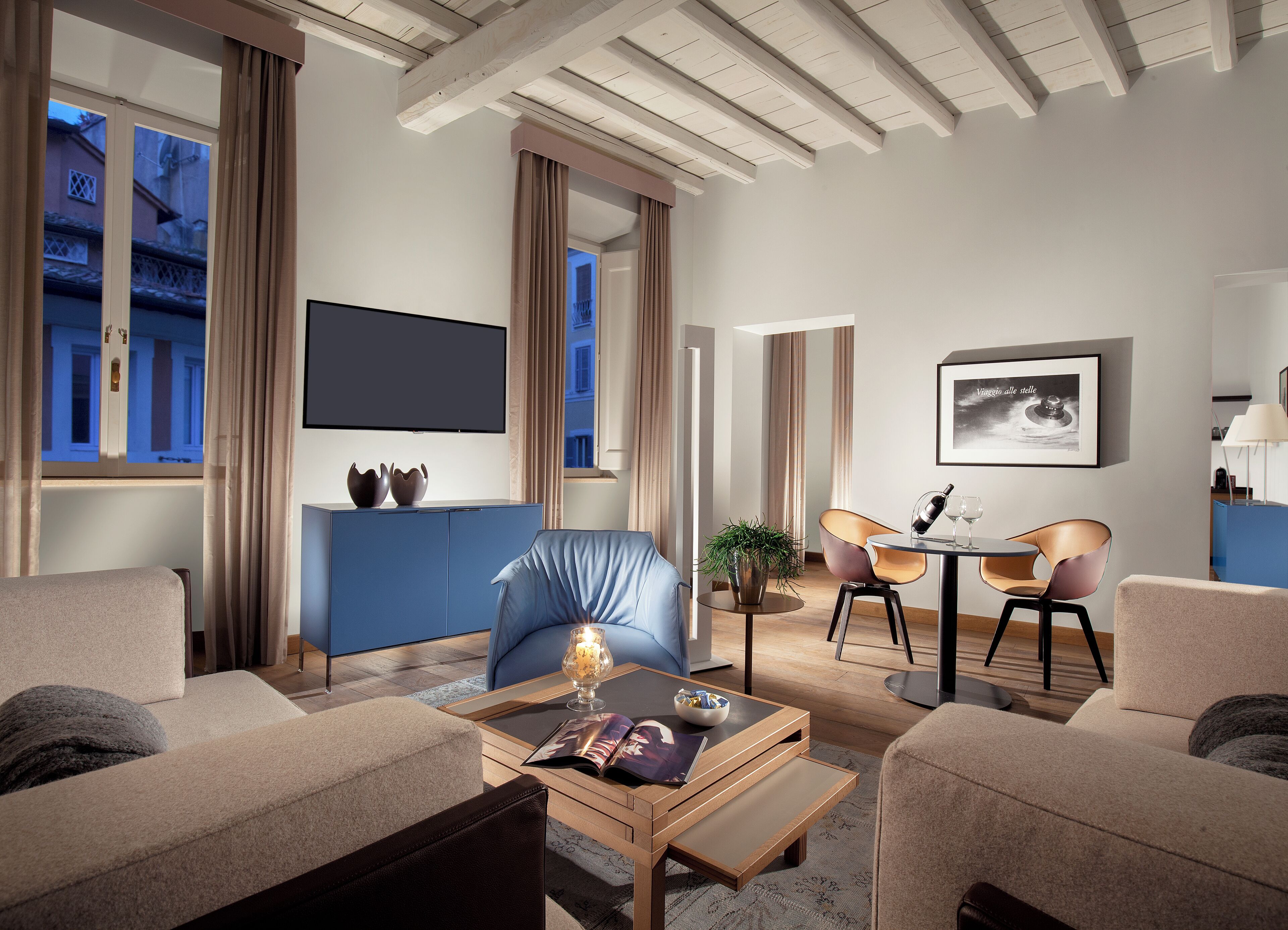 A modern living room with a sofa, armchairs, a coffee table, and a dining area with chairs and a table.
