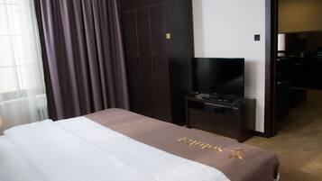 Une chambre d’hôtel avec un lit, un téléviseur posé sur un meuble, un bureau et une armoire.