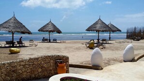 A beach with thatched umbrellas, lounge chairs, and decorative stones. - Kola Beach Resort (Malindi)