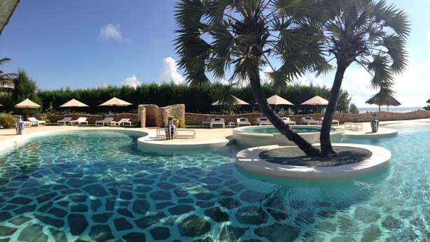 A pool area with clear water, lounge chairs, and umbrellas. - Kola Beach Resort (Malindi)
