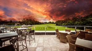 Un espace extérieur aménagé avec des meubles en osier, offrant une vue sur une pelouse bien entretenue et un terrain de golf.