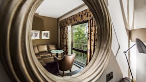 Une pièce dotée d’un grand miroir rond qui reflète un balcon, un canapé, une petite table et deux chaises.