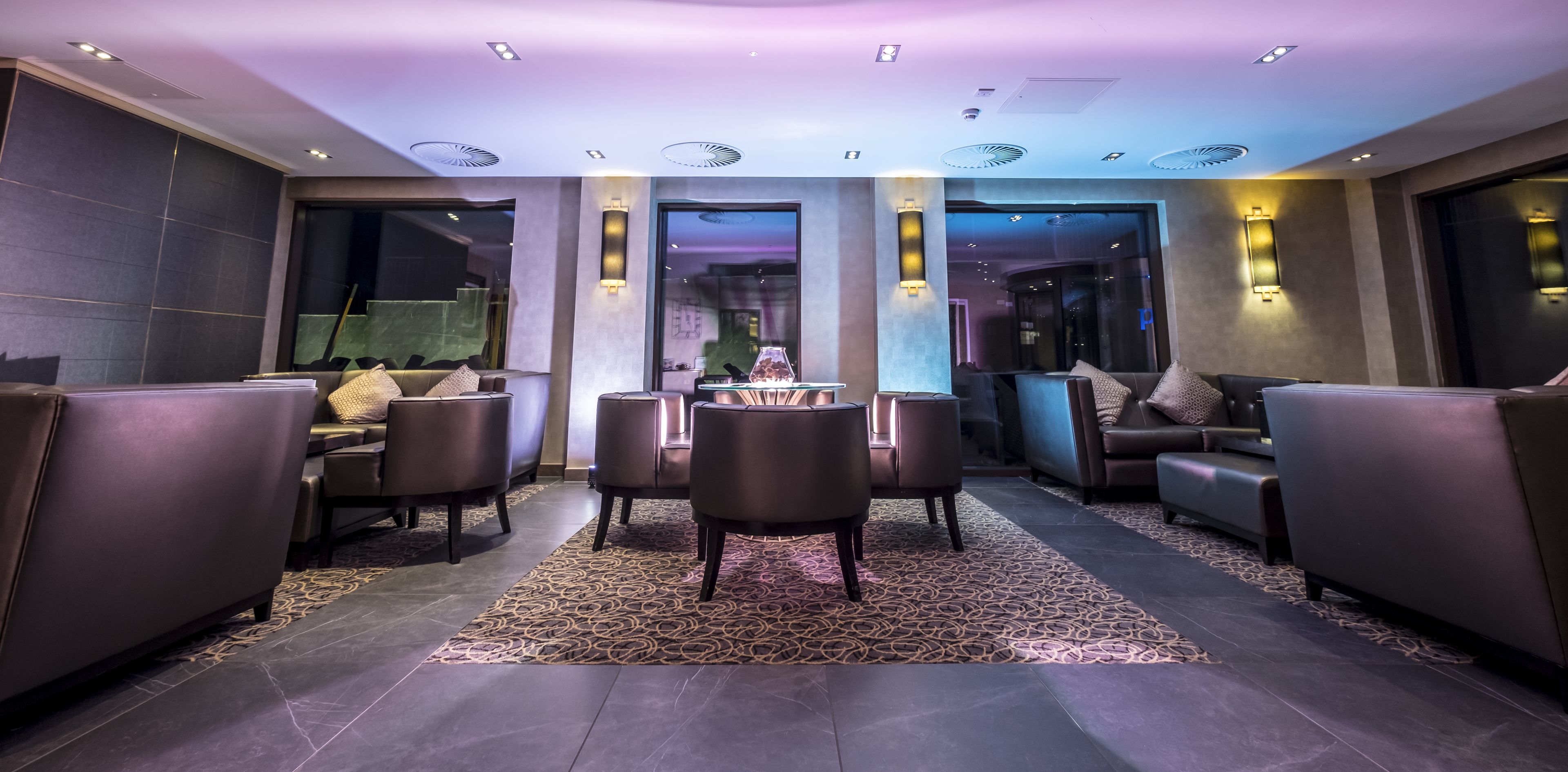 Een moderne lounge met leren banken, een ronde tafel en kamerbreed tapijt.
