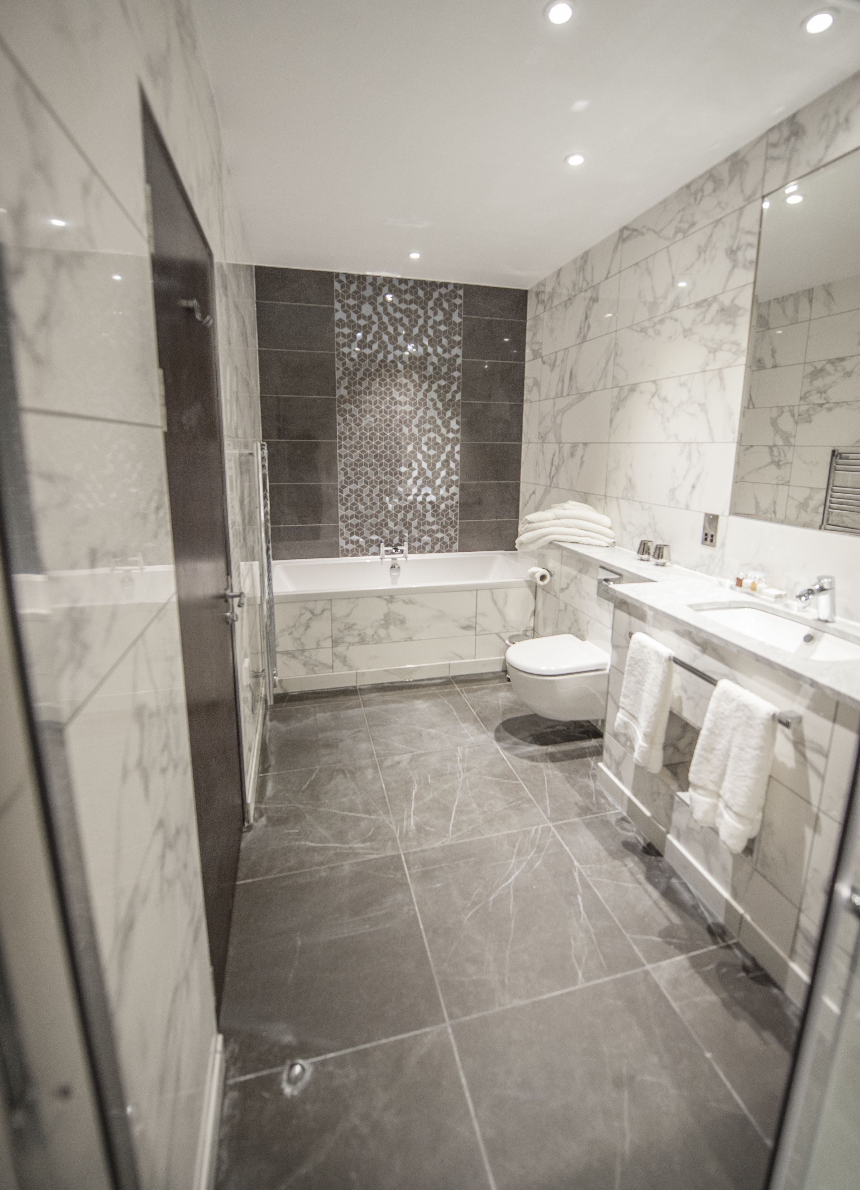Un baño moderno con ducha de vidrio, una bañera independiente y un tocador con espejo.
