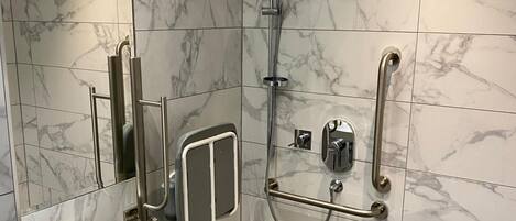 A modern bathroom with a walk-in shower, grab bars, and a white sink.