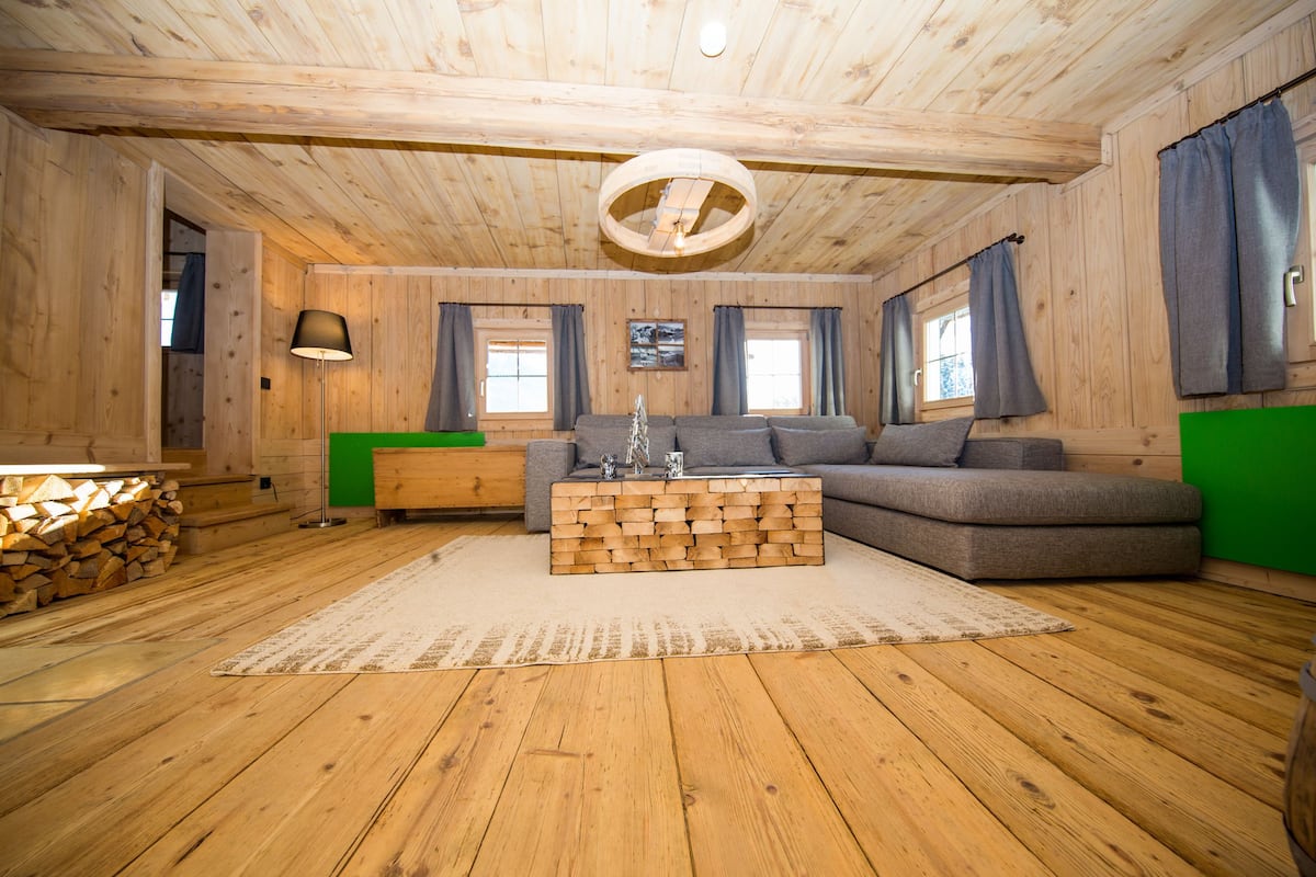 A wooden-paneled room with a sofa, a coffee table, and a lamp.