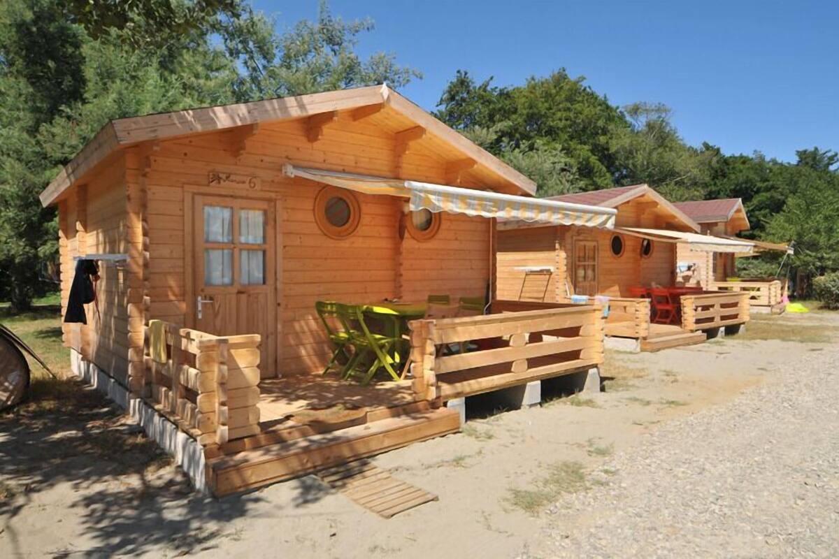 Une cabane en bois avec une véranda, une table et une chaise.