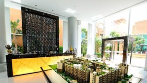 Une maquette d’un complexe résidentiel comprenant plusieurs immeubles de grande hauteur, un espace d’accueil agrémenté d’un paravent décoratif et une façade en verre permettant à la lumière naturelle de pénétrer.