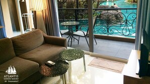 Un salon avec un canapé, une table basse en verre et une vue sur une piscine extérieure.