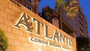 Une enseigne pour le complexe hôtelier Atlantis Condo Resort Paradise, avec une façade en pierre et des palmiers.