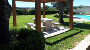 A wooden pergola structure with a table and benches in a garden setting. - Torres de Moreda (A Estrada)