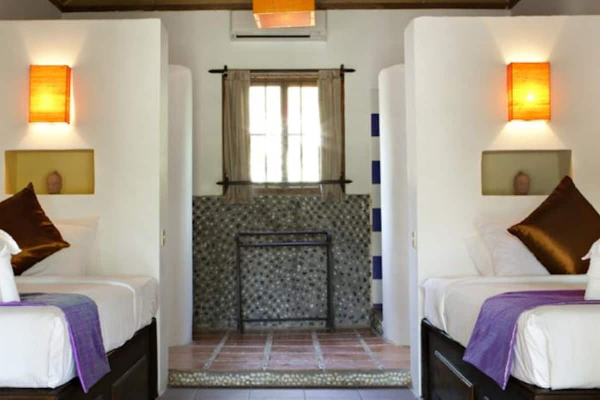 A hotel room with two beds, a small bathroom, and a tiled floor.
